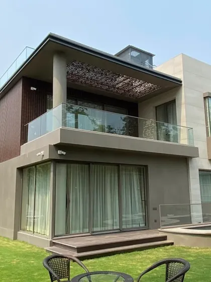 The completed rear view of the Gurgaon villa. The final build perfectly mirrors the render, including the wooden deck, the pergola on the terrace, and the overall proportions.