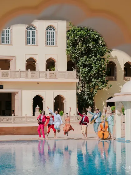A joyful jump by the pool with the band. This photo from the colorful carnival at Umaid Bhawan is full of energy and vibrant color.