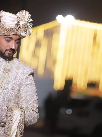 A portrait of the groom against a backdrop of blurred golden lights. This shot has a warm, celebratory feel, perfect for a wedding album.