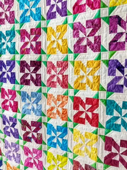 An angled view of the colorful pinwheel quilt, highlighting the texture.