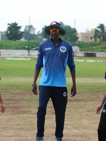 A coach tosses the coin for the captains before a Dasara Cup match, teaching them the official procedures of the game.