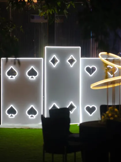 A chic and modern Diwali decor installation featuring illuminated playing card symbols. This makes for a perfect photo-op at a festive card party.
