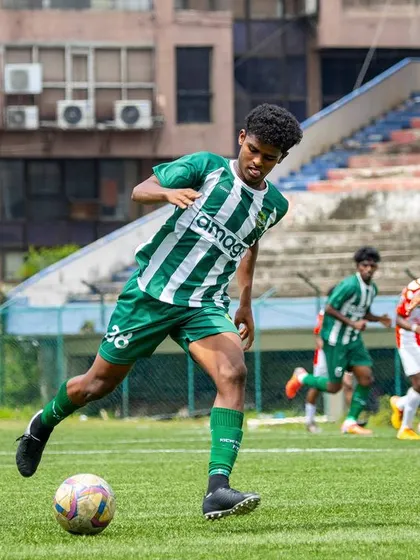 A dynamic action shot of a player dribbling at speed through the midfield, with the stadium stands in the background.