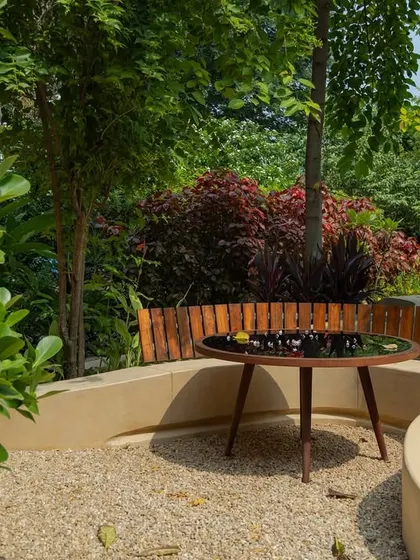 **Playfold, Ahmedabad:** The terrazzo bench is backed by a simple wooden fence, providing support and a warm, textural contrast. This area is perfect for family meals or small gatherings, seamlessly integrated into the garden.