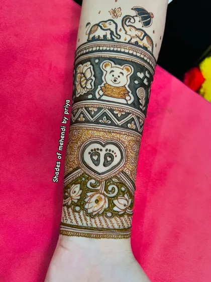 A close-up of the arm portion of the baby shower design. You can see the detail in the teddy bear, the baby footprints in a heart, and the playful elephants.