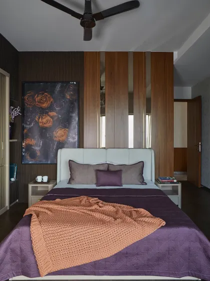 This master bedroom was designed for a client who wanted a bold, dark, and enigmatic space. It features leather-clad wardrobe shutters, a rich veneer backdrop, and metallic accents.