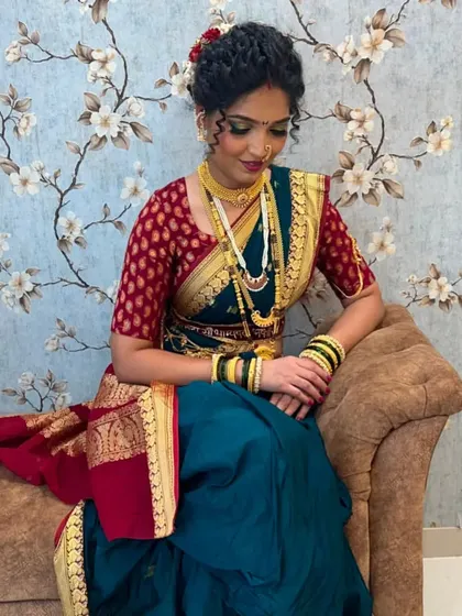 A seated portrait of a Maharashtrian bride, capturing the elegance of the Paithani saree and the traditional gold jewelry. The makeup is kept classic and radiant.