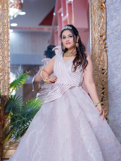 The full view of this princess-style gown shows its elegant design and sparkling fabric, reflected in the grand mirror behind.