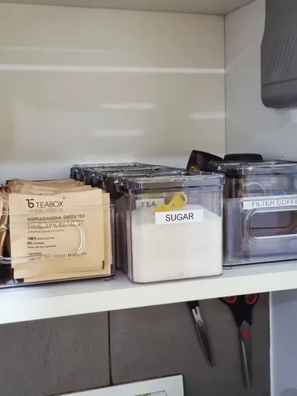 Creating a cozy beverage corner is simple. We used clear bins to group tea bags, sugar, and coffee, making it a dedicated and inviting spot in the kitchen.