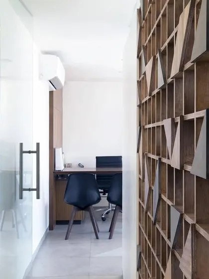 A view from the corridor into one of the consultation rooms. The glass partition allows light to flow through the space, while the wooden screen on the right adds warmth and texture.