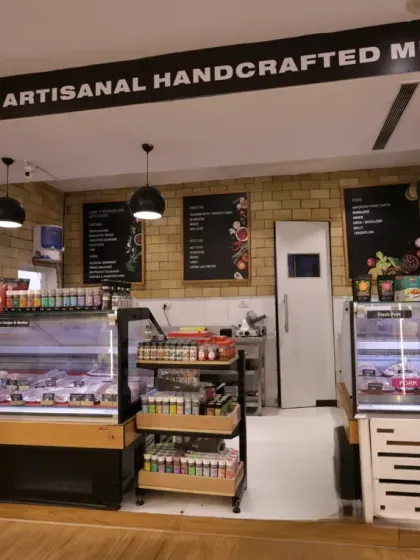 This dedicated section for fresh and artisanal meats uses a clean, deli-style design with subway tiles and clear signage. The refrigerated displays are integrated seamlessly, ensuring product freshness while maintaining a high-end butcher shop aesthetic.