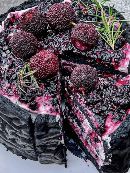 A stunning and unique black forest cake with a modern twist. The dark chocolate cake is topped with a rich berry compote and fresh lychees or similar fruit.