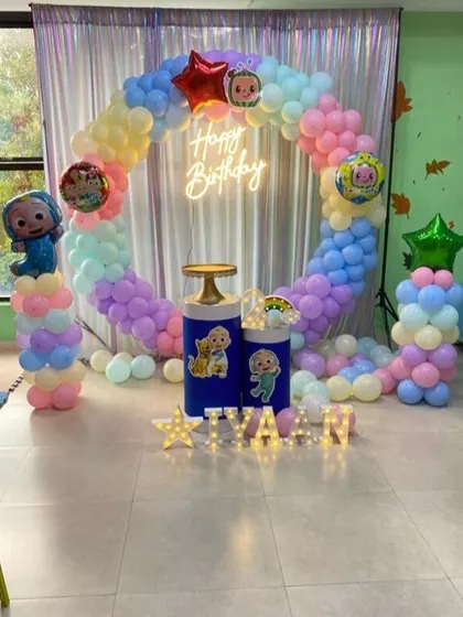 A Cocomelon and Masha and the Bear themed birthday party. This setup combines elements from both shows, with a pastel balloon ring and character foil balloons.