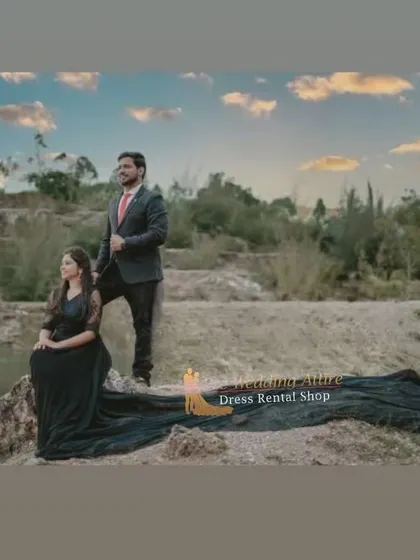A couple in a rugged, natural landscape. The woman's black trail gown stands out against the earthy tones, while the man's suit adds a touch of formality.