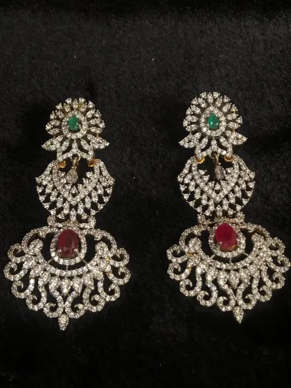 These stunning CZ chandelier earrings with ruby and emerald stones are perfect for adding a touch of glamour to any outfit.