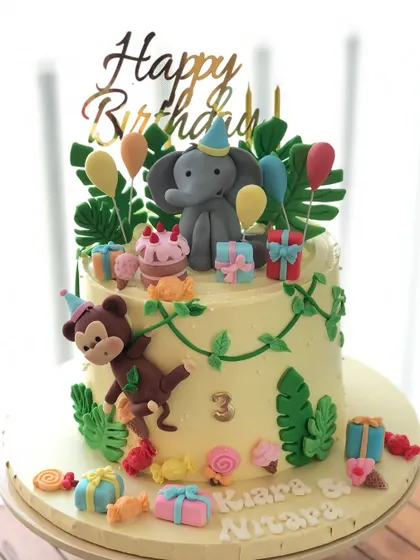 A full view of the jungle party cake, with presents, balloons, and sweet treats for the animals.