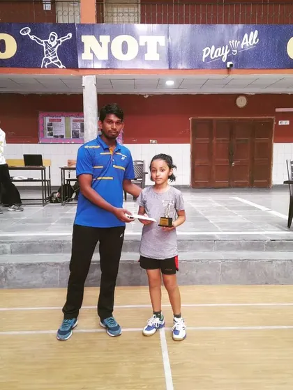 A young girl receiving her trophy and prize, showing the success of our junior development program.