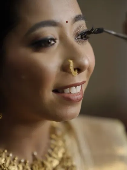 A close up of the makeup process, showing the careful application of false eyelashes to enhance the eyes for a more dramatic, yet natural look.