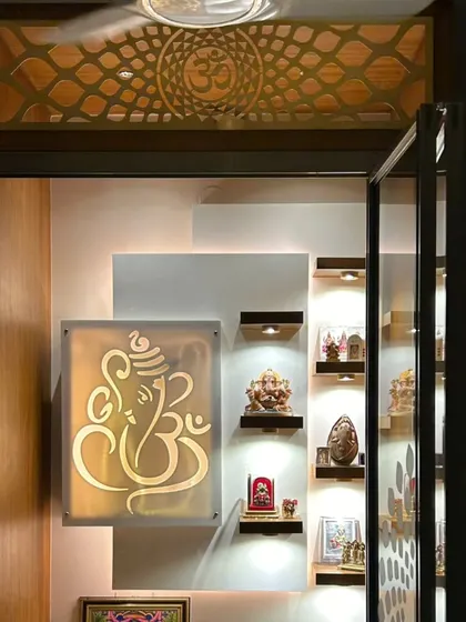 A beautifully lit puja room featuring a backlit Ganesha design on glass, creating a divine and serene focal point.