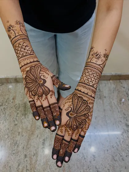 The peacock is a timeless symbol of grace and beauty in mehendi art. Here, I've made it the centerpiece of the design, with intricate feather details on the palm and geometric patterns extending up the wrist.