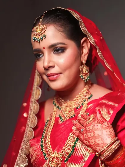 A close-up showing the details of her henna and the beautiful contrast of the green beads in her gold jewelry.