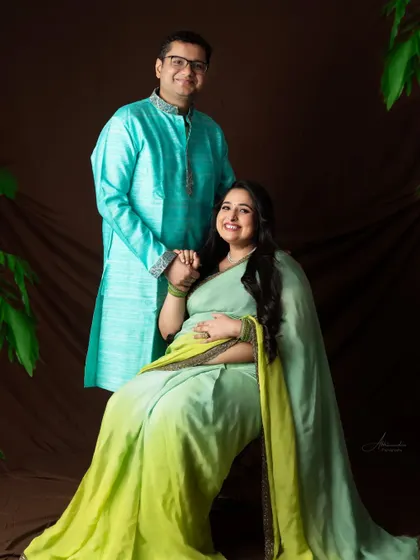 A formal and sweet portrait. The couple holds hands, sharing a moment of connection during their traditional maternity session.