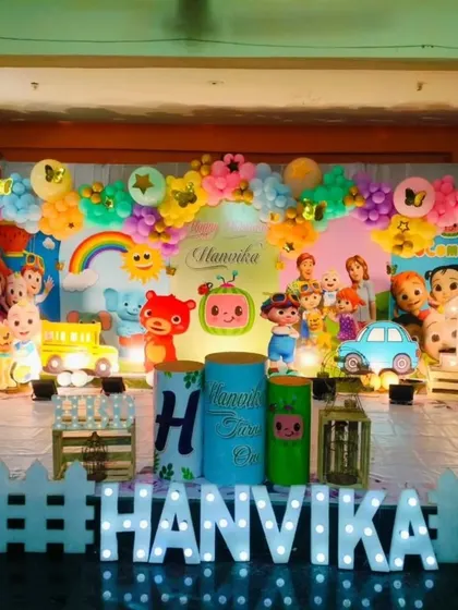 A vibrant and colorful Cocomelon birthday party. The stage is filled with all the beloved characters, a rainbow, and a white picket fence, creating a cheerful and immersive setting.