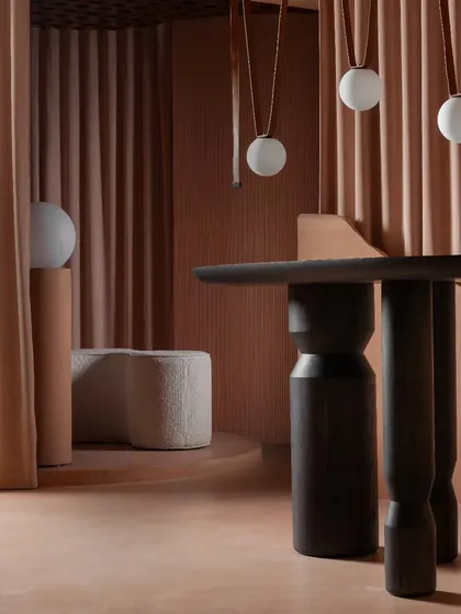 A close-up on the custom furniture and lighting. The dark wood of the table provides a grounding contrast to the soft tones of the room, while the leather-strapped pendants add a touch of rustic elegance.