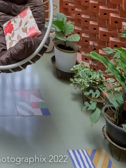 A detail of the cozy balcony, showing the comfortable swing chair and potted plants against the backdrop of the textured brick wall.