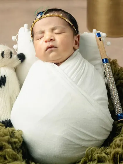 A close-up of our little Krishna, swaddled in white with his flute and a tiny knitted cow by his side. The details make the theme come alive.