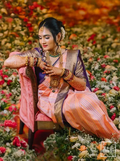 The bride seated gracefully on a chair amidst a sea of flowers, looking like royalty. This is a truly stunning and artistic bridal portrait.