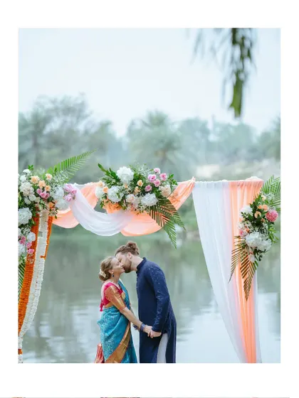 A romantic kiss under a beautiful floral arch by the water, a perfect ending to a beautiful ceremony.
