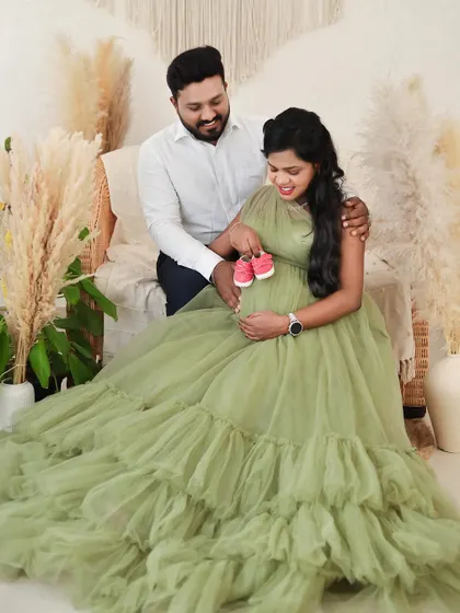 A happy couple in our boho studio, holding up a pair of pink baby shoes. This is a wonderful way to announce you are expecting a girl.