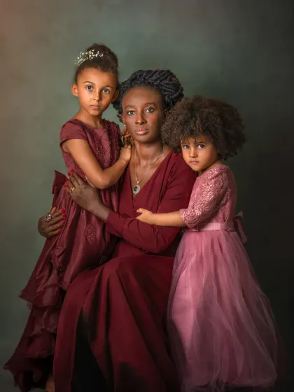A mother and her two daughters, posed like a classic painting. The rich colors and the subjects' intense gazes create a powerful, artistic portrait that speaks of family strength and love.