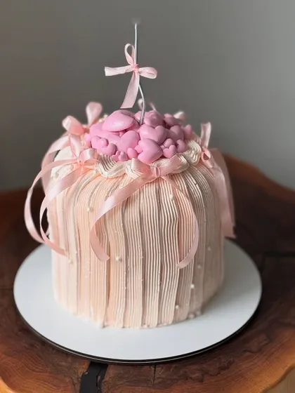A pretty pink cake with dreamy hearts and bows, featuring a unique textured finish.