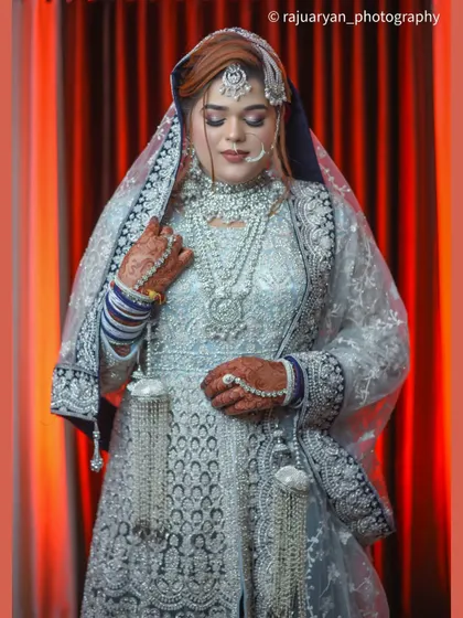 A classic bridal pose, with the bride looking down, showcasing her stunning necklace and the fine workmanship of her veil and dress.