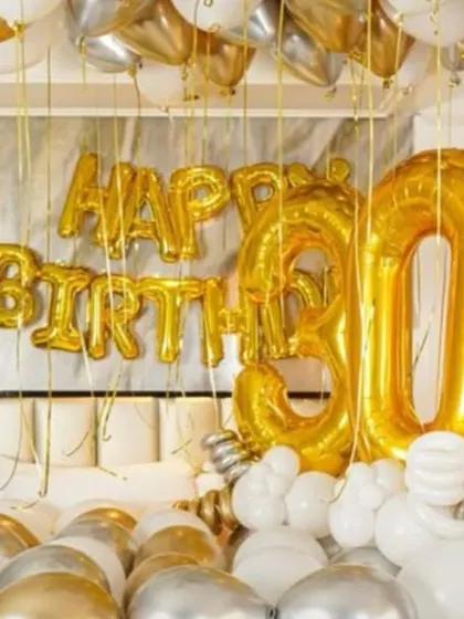 A detailed shot of the giant '30' foil balloons and the "Happy Birthday" banner over the bed.