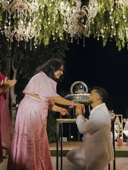The groom gets on one knee to propose during the engagement ceremony.