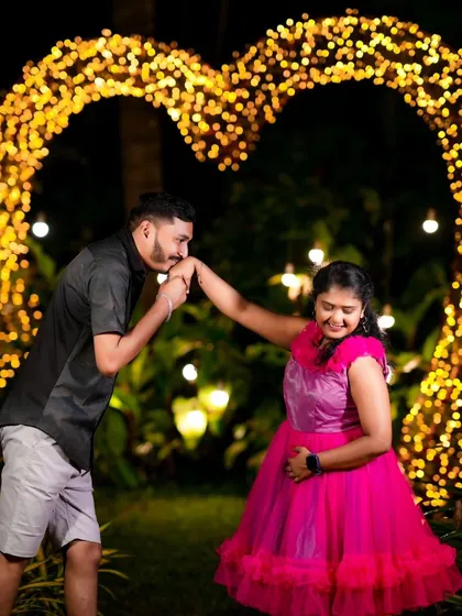 A classic romantic gesture in front of a heart-shaped arch of lights. This is a perfect shot for any pre-wedding album.