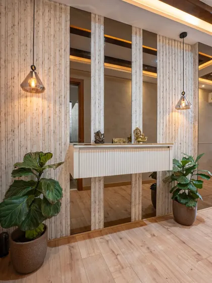 This beautifully designed foyer makes a striking first impression with its minimalist mirrored paneling, warm pendant lighting, and lush fiddle-leaf fig plants creating a sophisticated entrance.
