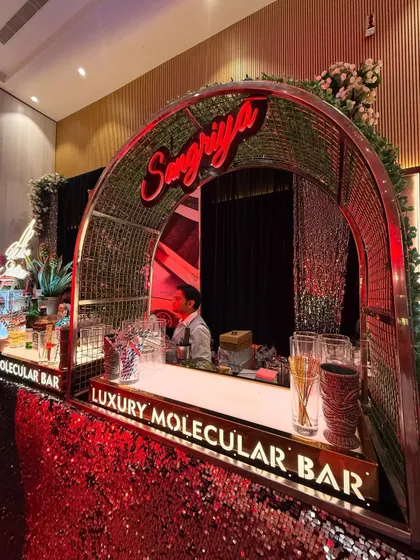 A high-angle shot of the 'Sangriya' station, highlighting the lush greenery and arched design against the sparkling red sequin bar.