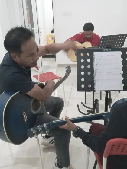 An instructor helps a student with their guitar chords. We make sure every student gets the basics right.