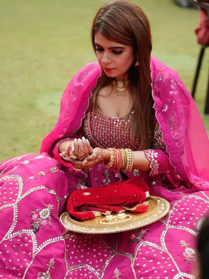 A candid photo of a client during her Karwa Chauth puja, with my mehendi design visible on her hands.