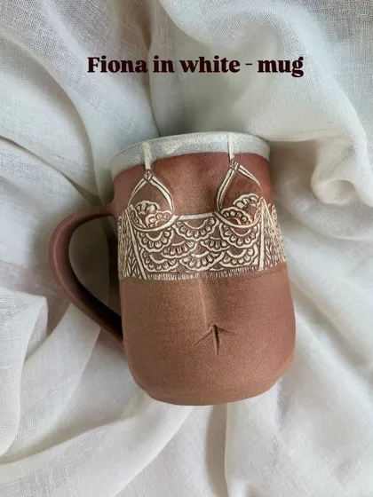 The 'Fiona' mug in white from the Déesse Collection. The design is softer, reflecting a different personality, but with the same attention to hand-carved detail that defines these pieces.