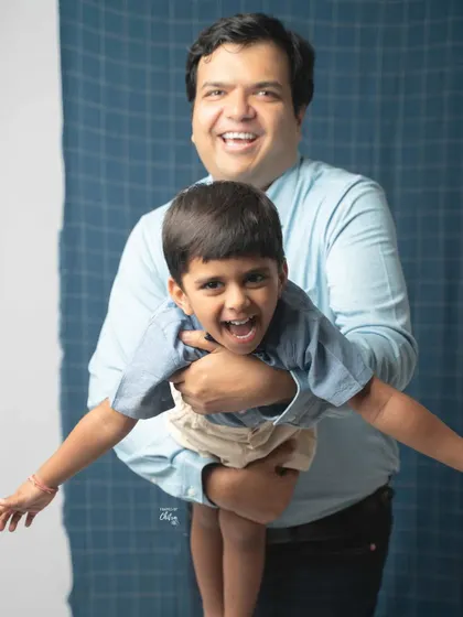 The pure energy and laughter between a father and son. I encourage playful moments like this during my family photoshoots to capture genuine expressions. This candid shot against a simple studio backdrop highlights their joyful connection.