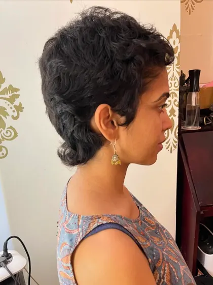 A side view of the curly mullet, showing the shorter layers on top and length at the back.