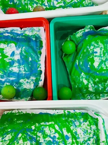 The finished products from our collaborative marble painting activity. The swirling patterns of blue and green look like little Earths, created through teamwork and movement.