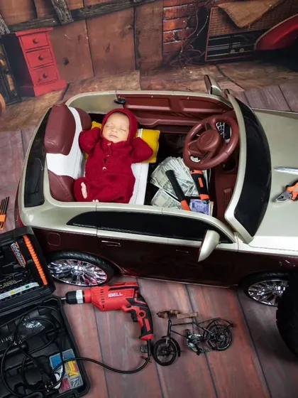 This little one is taking a nap after a hard day's work in the garage. The detailed setup with tools, a tire, and a toy car makes for a very convincing scene.