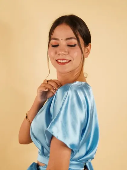 A beautiful sky blue satin blouse with bell sleeves and a tie-waist. This piece is perfect for a fresh and modern look.