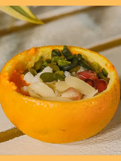 A close-up of our "Cosmic Dawn" dessert, showcasing the fresh ingredients and creative presentation inside a hollowed-out orange.